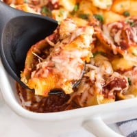 stuffed shells in a white baking dish with a spoon