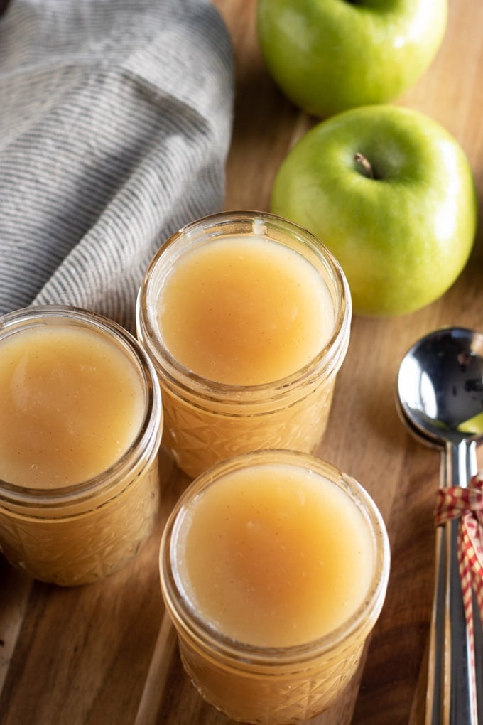homemade applesauce in jars with granny smith apples and a towel