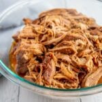 pulled pork in a glass bowl on a white background