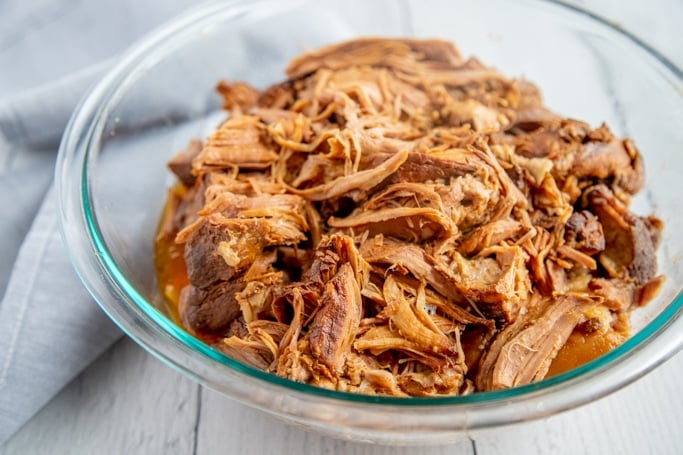 pulled pork in a glass bowl on a white background