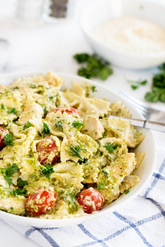 pasta with tomatoes and pesto in a white bowl