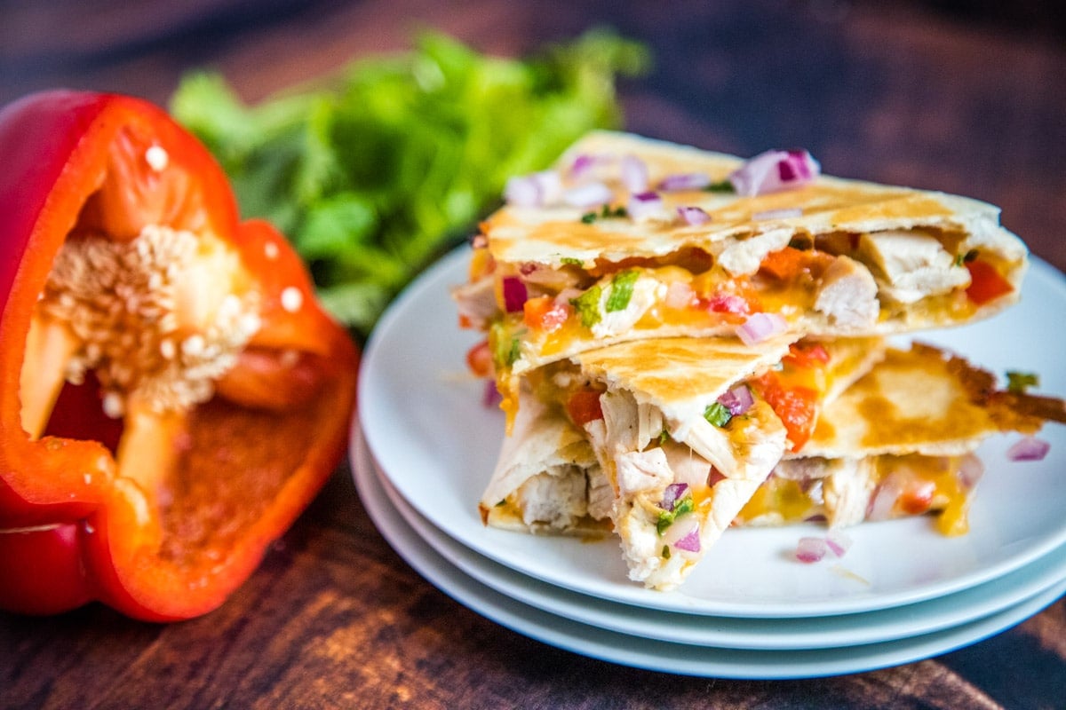 chicken quesadillas on a stack of white plates