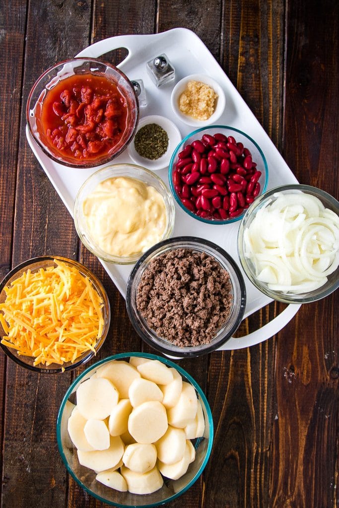 ingredients to make cowboy casserole laid out on a wooden board with a white tray