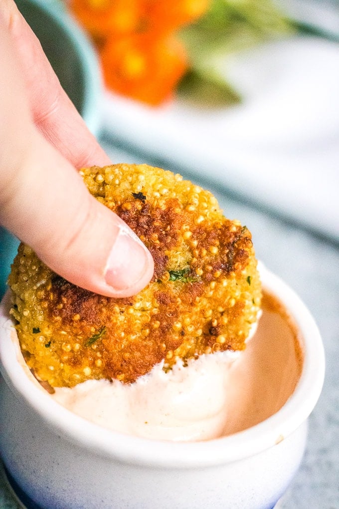 quinoa patties being dipped in sriracha sour cream dip