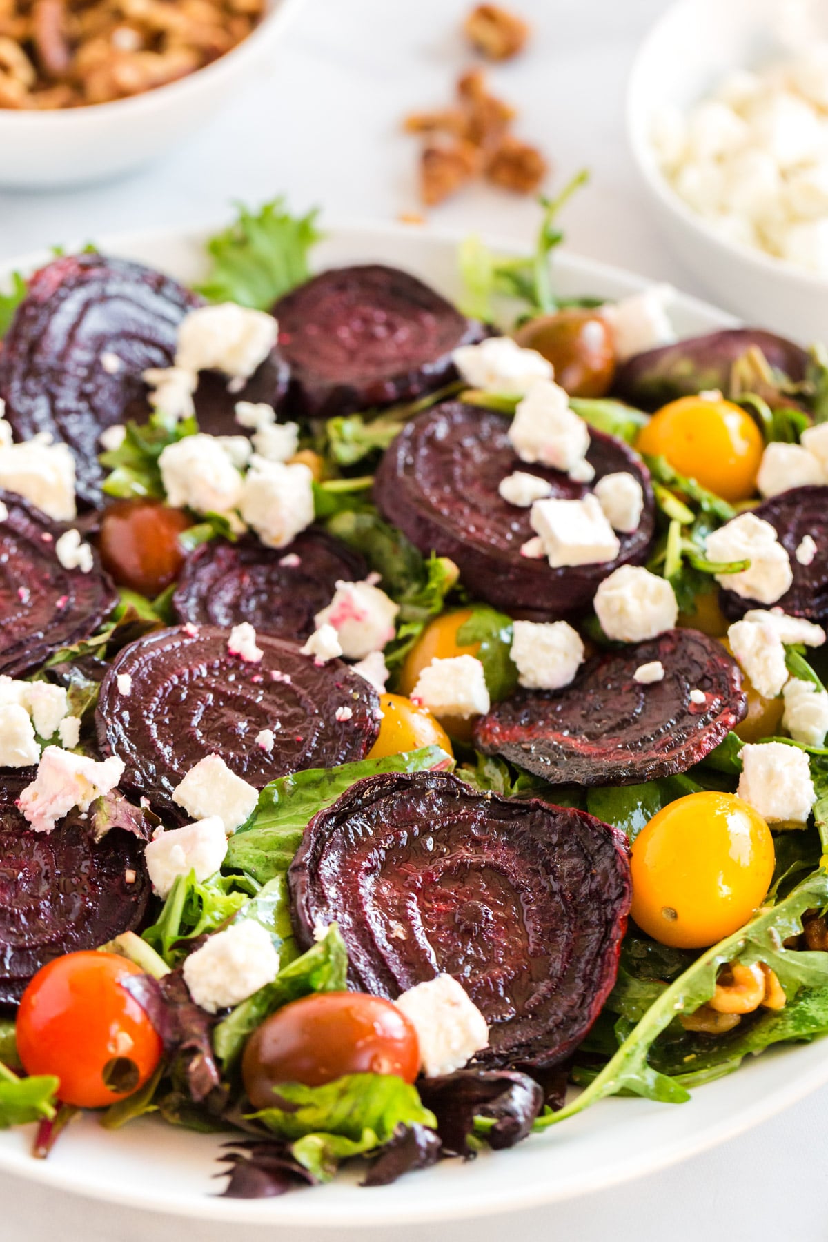 a beet salad close up with red and yellow tomatoes, in a white bowl