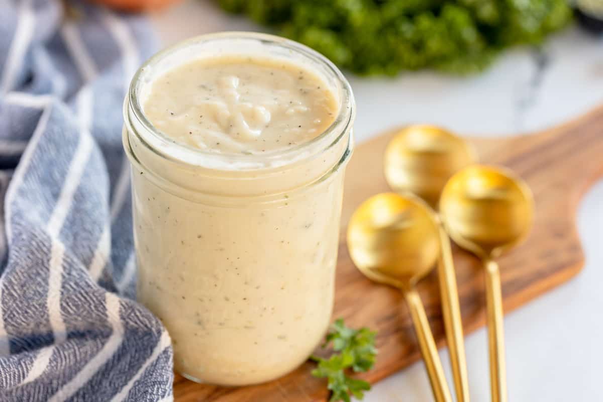 homemade cream of chicken soup in a jar on a wooden board with gold spoons.