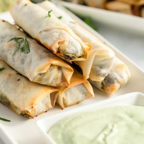 southwestern egg rolls on a white plate with avocado dipping sauce