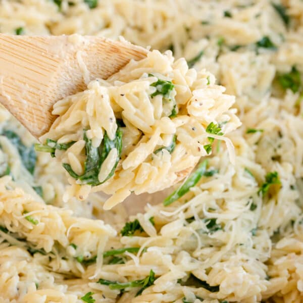 Spinach orzo in a skillet with a wooden spoon