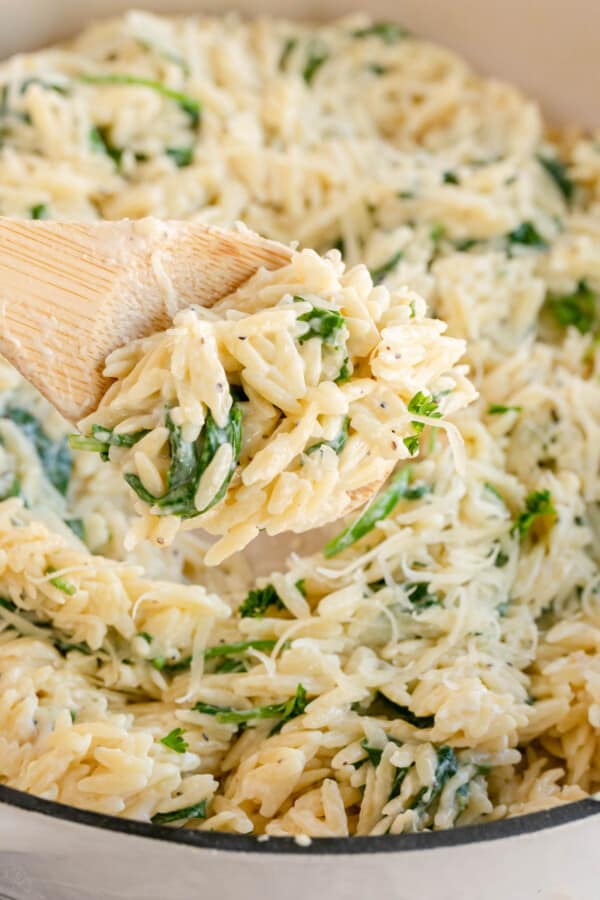Spinach orzo in a skillet with a wooden spoon