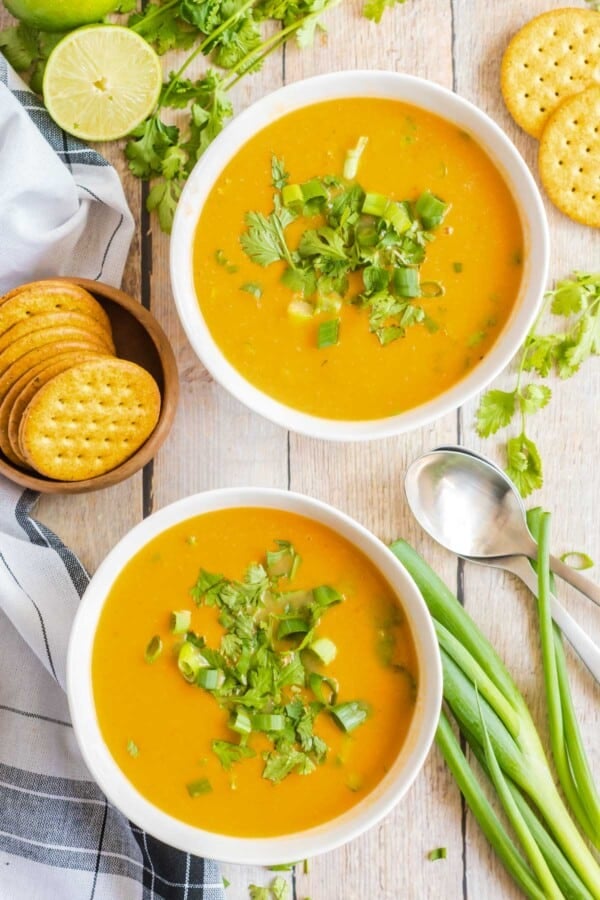 Sweet Potato Soup in two white bowls with greens