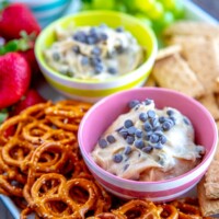 cookie dough dip with pretzels, strawberries, graham crackers and grapes on a white platter