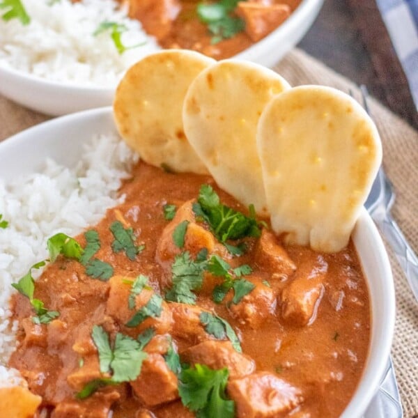 chicken tikka masala in a white bowl with mini naan