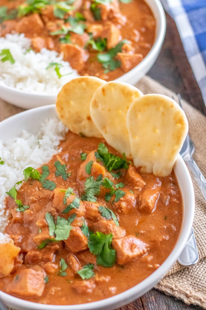 chicken tikka masala in a white bowl with mini naan