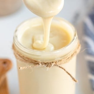 homemade sweetened condensed milk on a spoon.