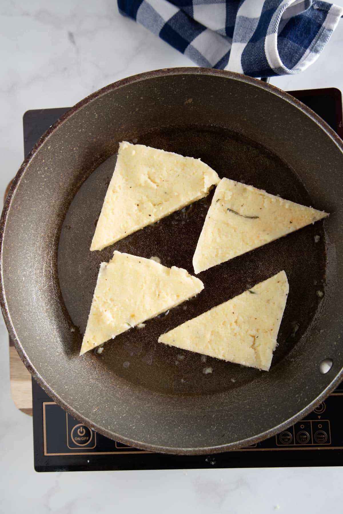 black skillet with triangles of polenta being fried