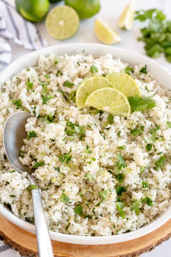 cilantro lime rice in a white bowl with lime wedges
