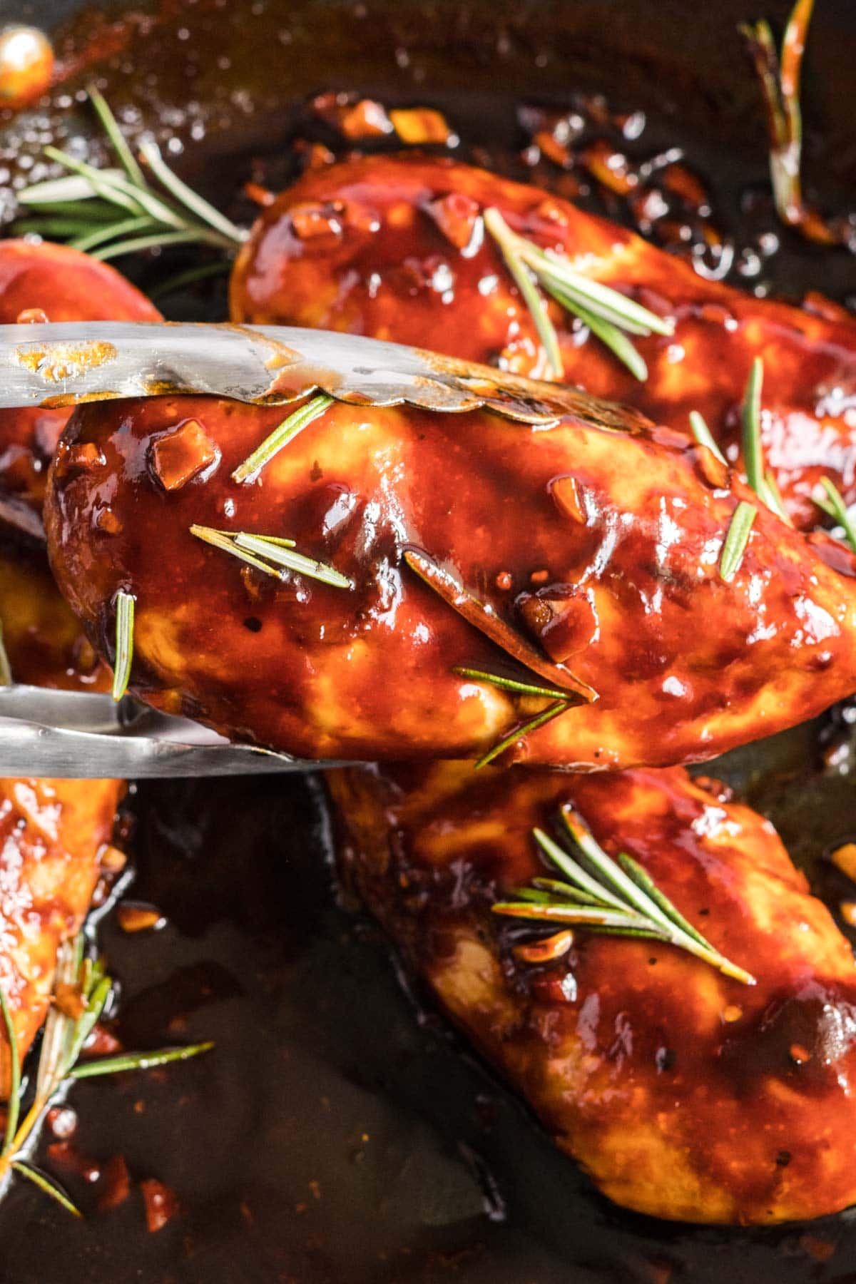 glazed chicken being held in tongs