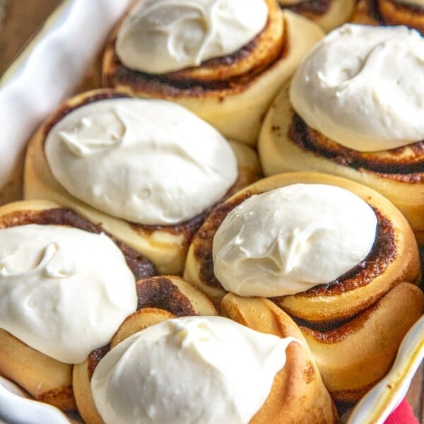 cinnamon rolls with frosting in a white baking dish