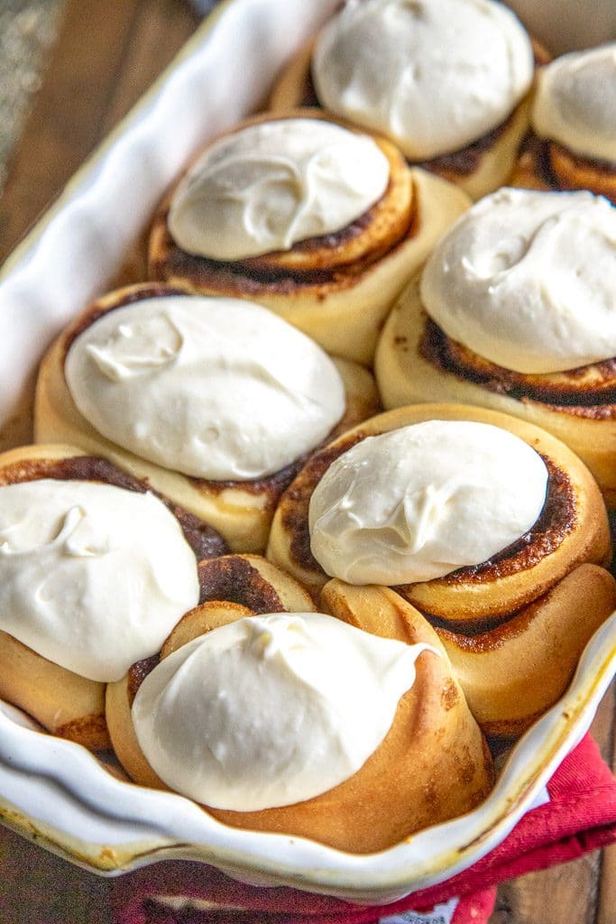 cinnamon rolls with frosting in a white baking dish
