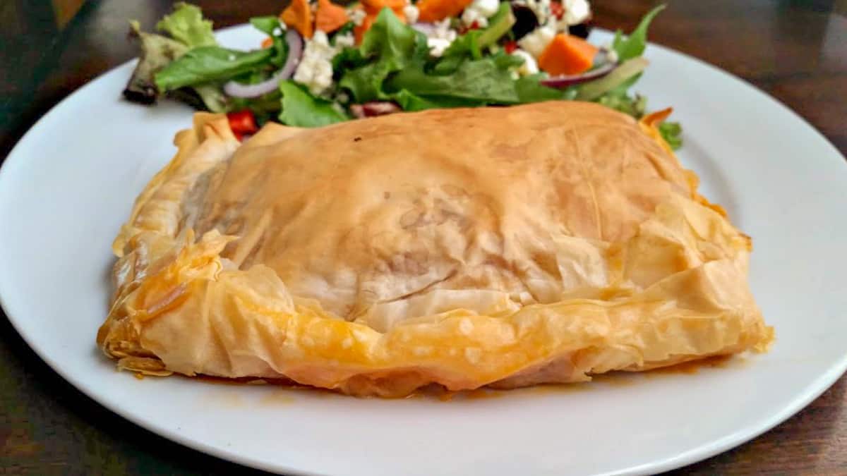 phyllo meat pie on a plate with salad.
