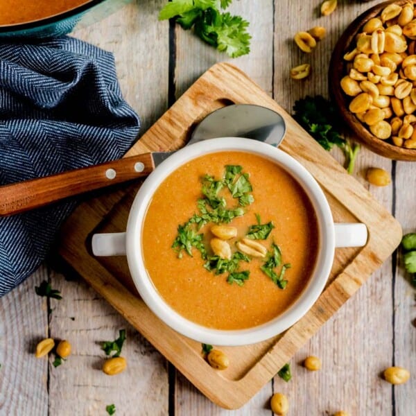 Peanut soup in a white bowl on a wooden board