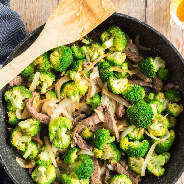 beef and broccoli in a wok with a wooden spoon