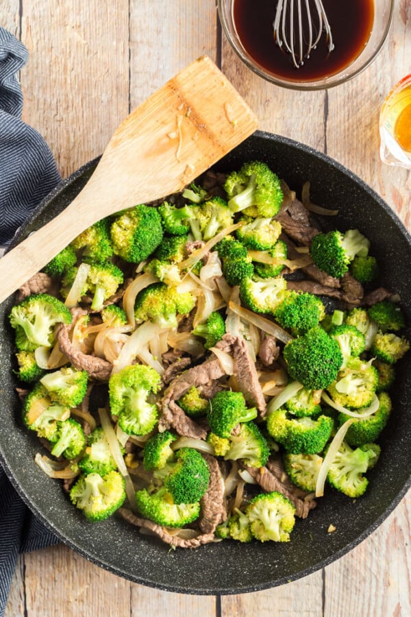 beef and broccoli in a wok with a wooden spoon