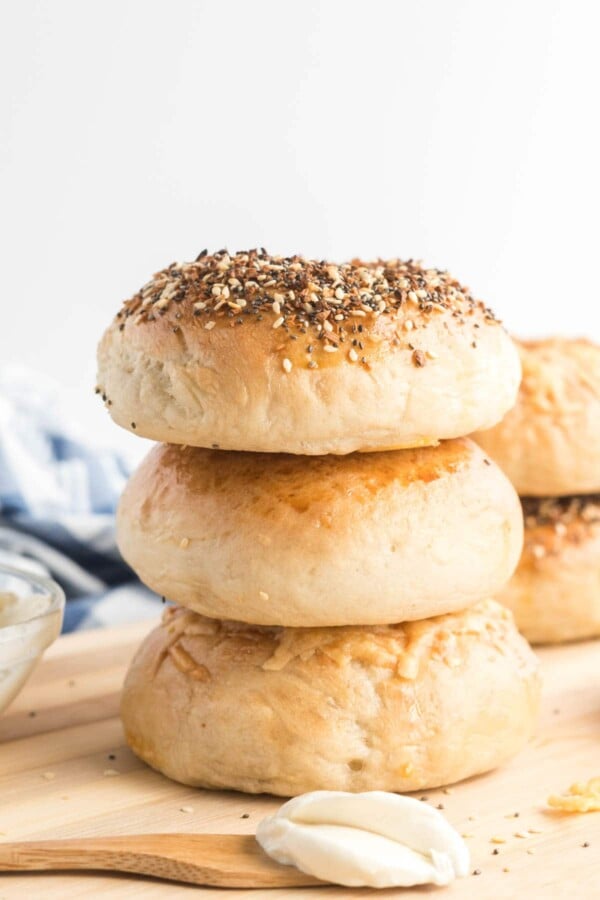homemade bagels stacked, with a spoon and cream cheese schmear