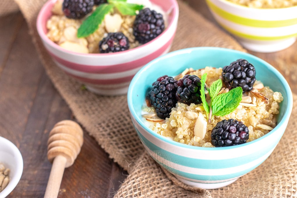 breakfast quinoa in colorful bowls with a honey dipper