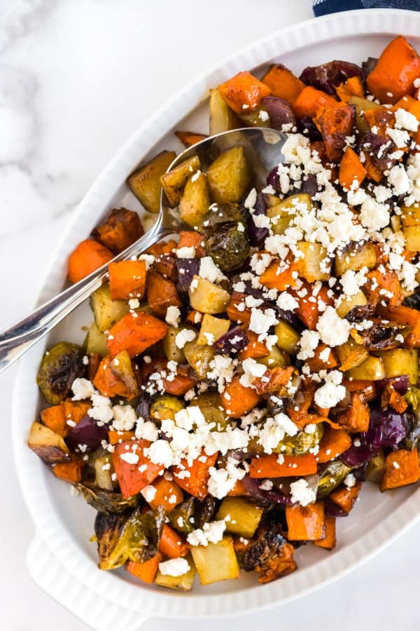 oven roasted vegetables on a white platter with a spoon