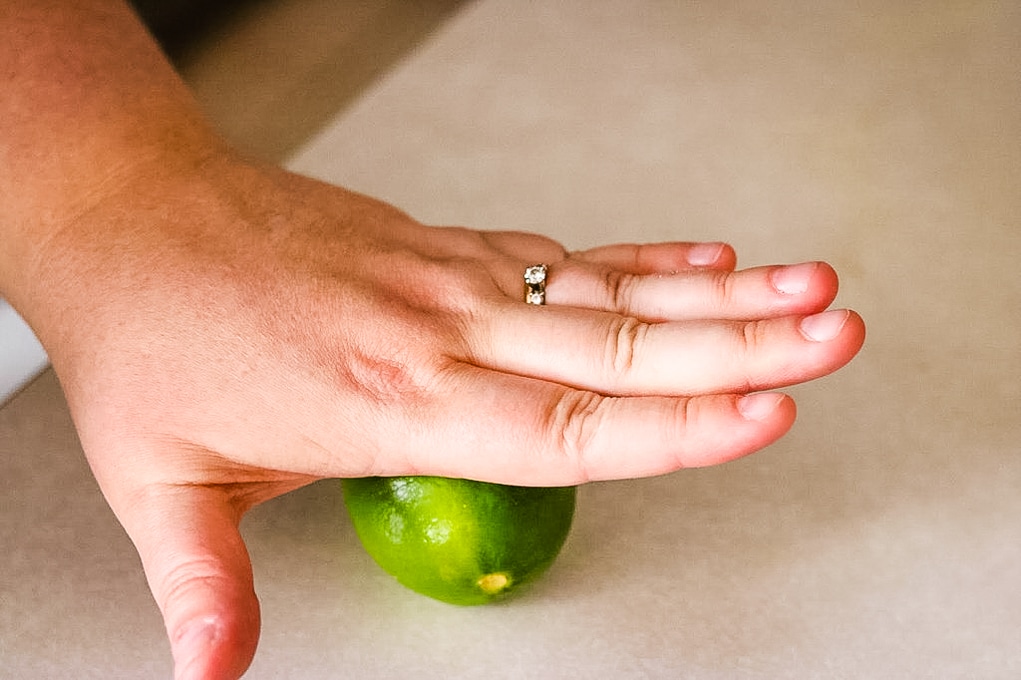 a hand squishing a lime