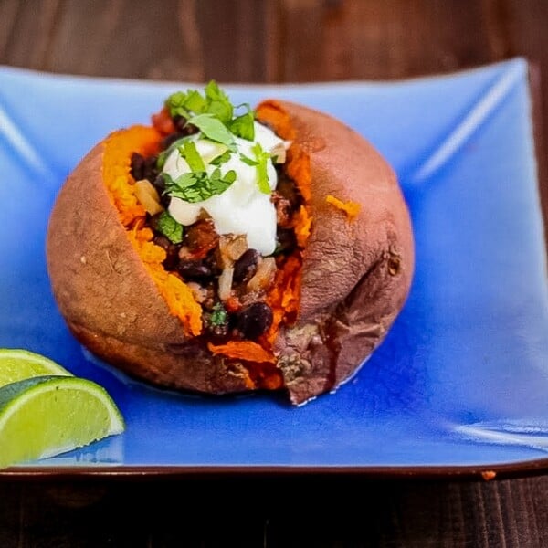 baked sweet potato with warm black bean salad on a blue plate