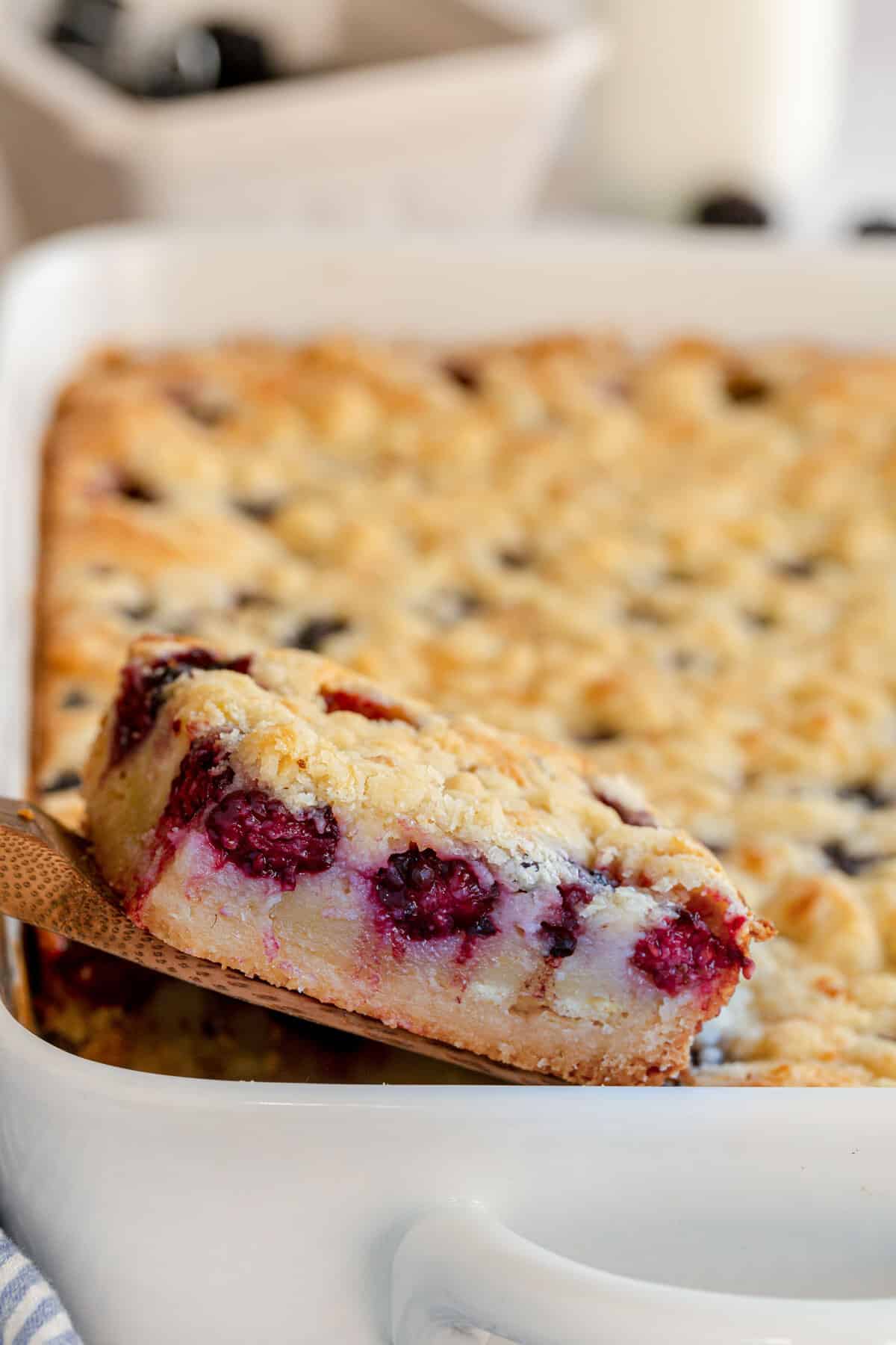 blackberry pie bars in a baking dish being removed