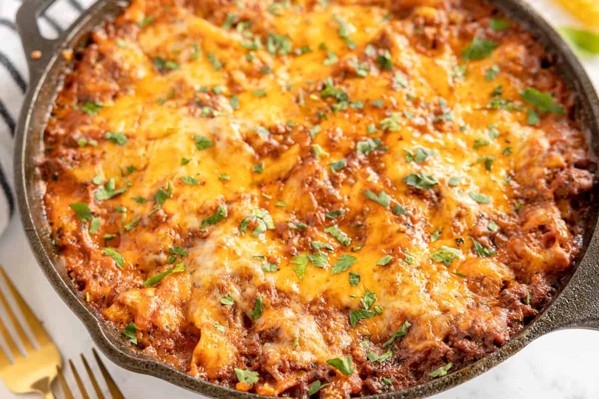 cast iron skillet lasagna with a spoon taken out