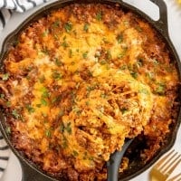 lasagna made in a skillet with parsley and 2 forks