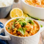 chicken stew in a white bowl with lemon and cilantro.