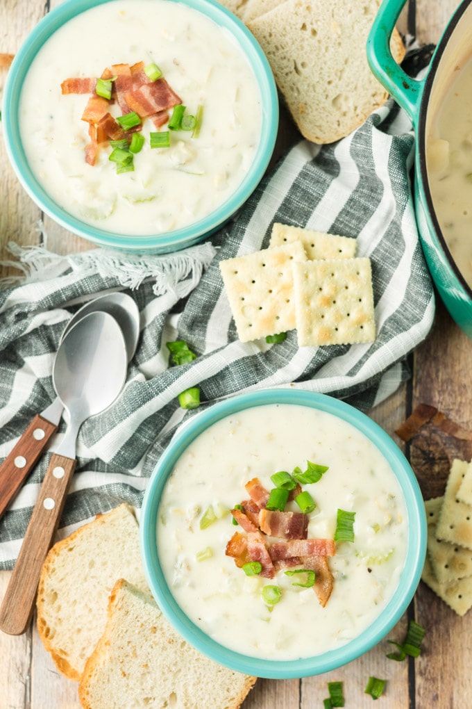 clam chowder in bowls with crackers and blue and white linen napkin