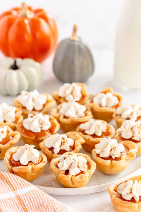 mini pumpkin pies on a white platter with ceramic pumpkins in the background