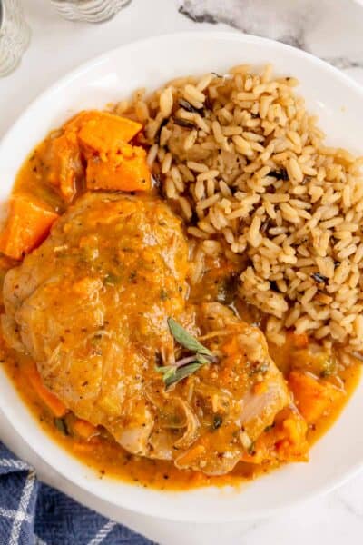 braised chicken thighs with brown rice in a white bowl