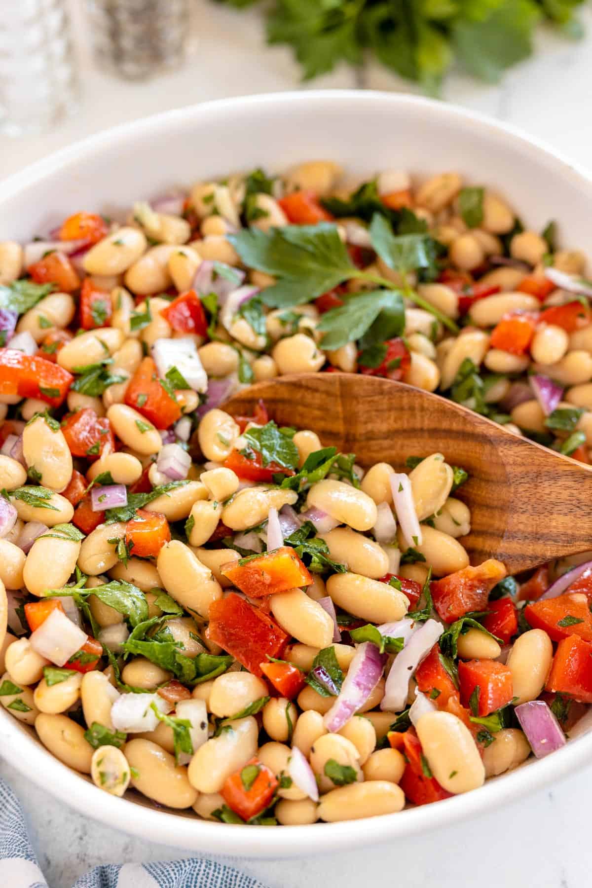 white bean salad in a white bowl with utensils.