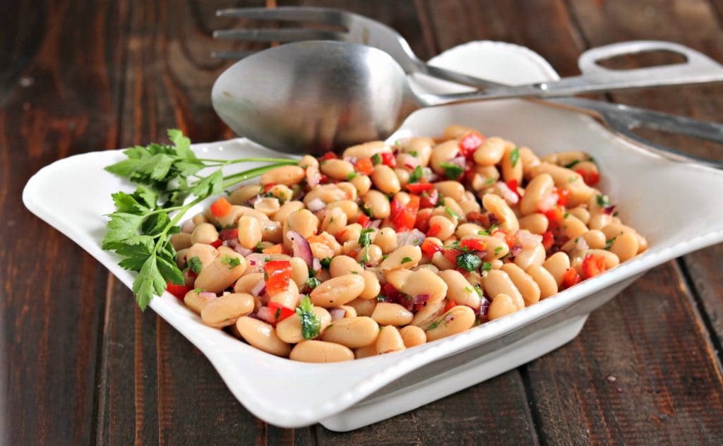 white bean salad in a white bowl with utensils