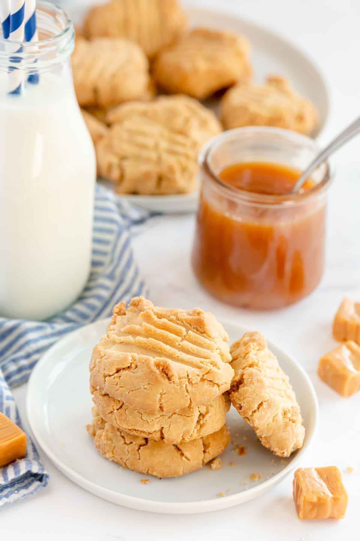 caramel cookies on a white plate with a bottle of milk