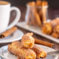 cinnamon cream cheese roll ups on a white plate with a coffee cup