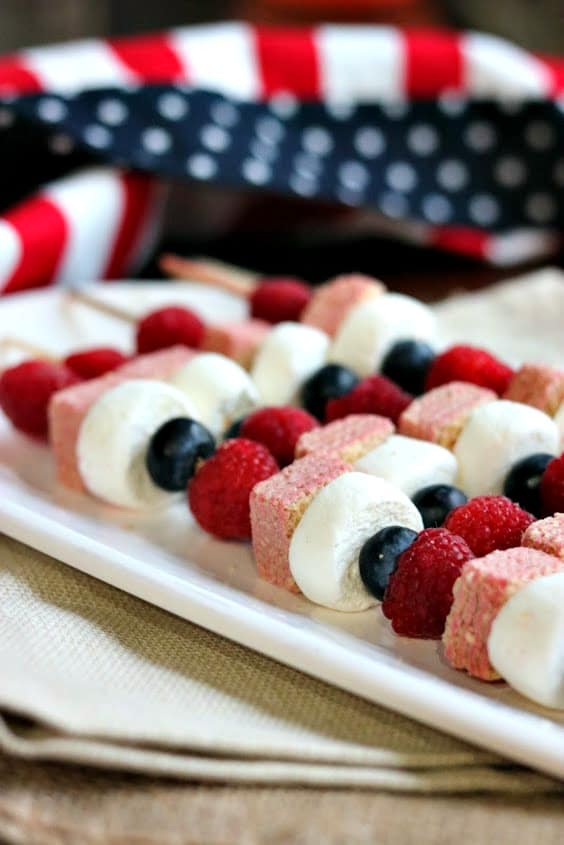 fruit and cookie kabobs on a white platter