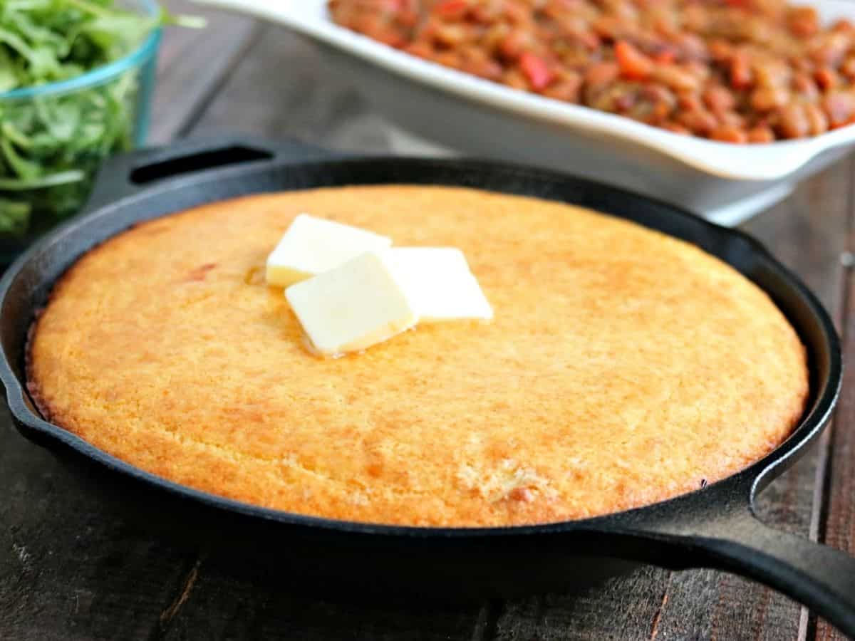 cast iron skillet of cornbread with butter on top