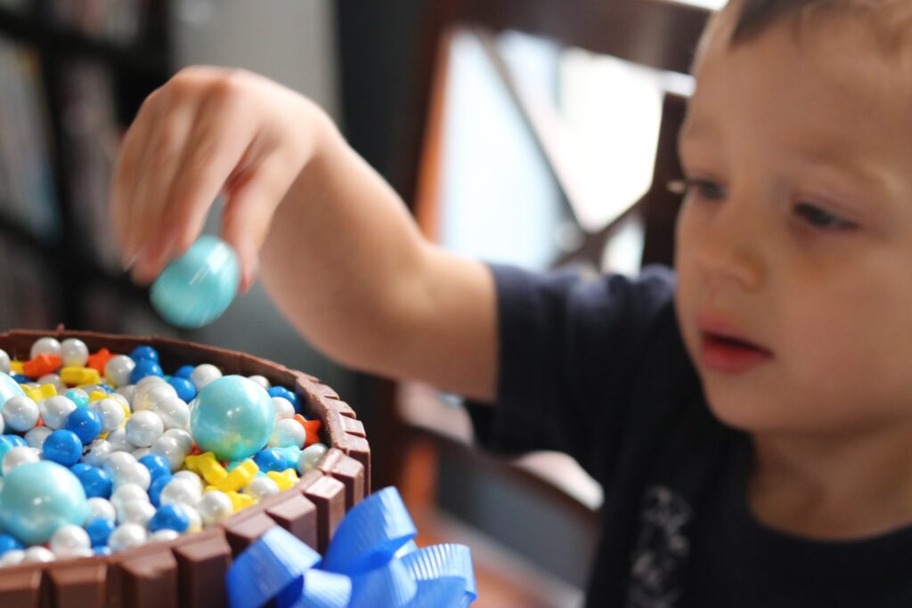 boy adding candies to kit kat cake