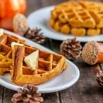 pumpkin waffles in quarters on a white plater with pinecones