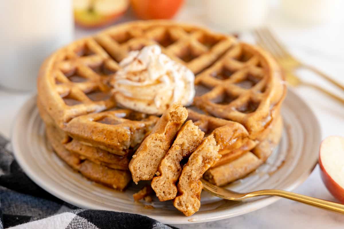 apple cinnamon waffle with whipped cream and apples and cinnamon stick.