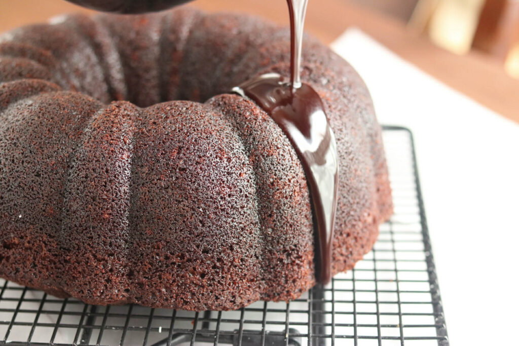 pouring chocolate glaze over baked bundt cake