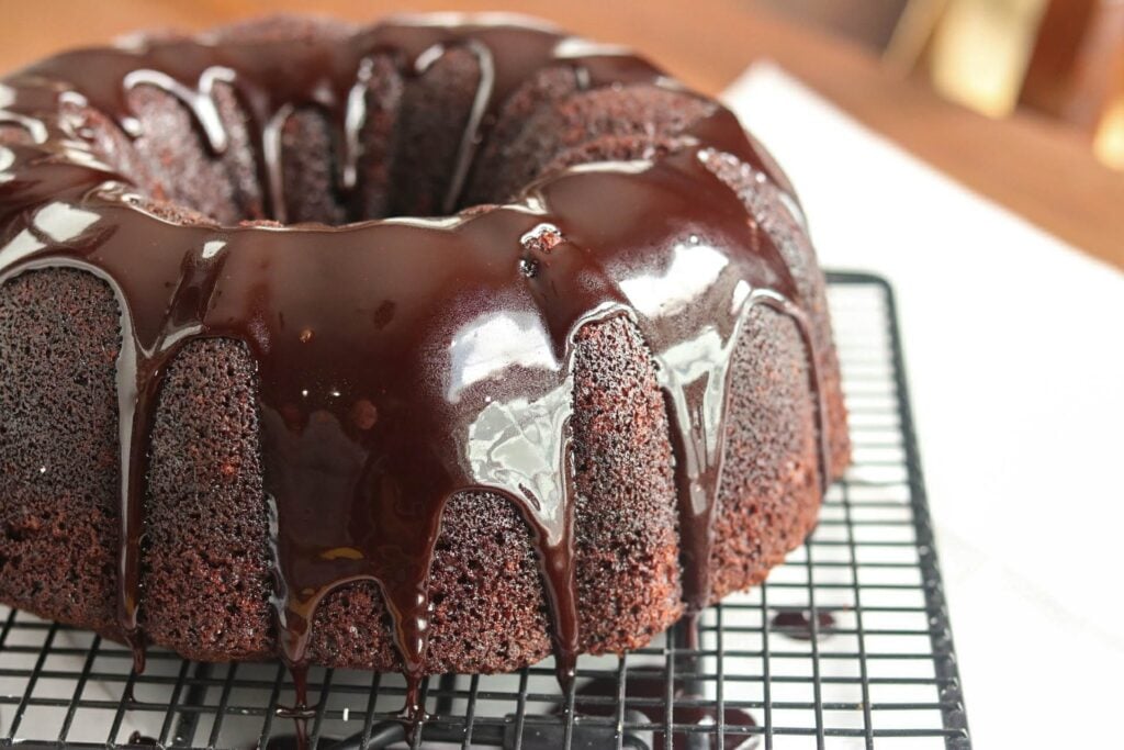 pouring chocolate glaze over baked bundt cake